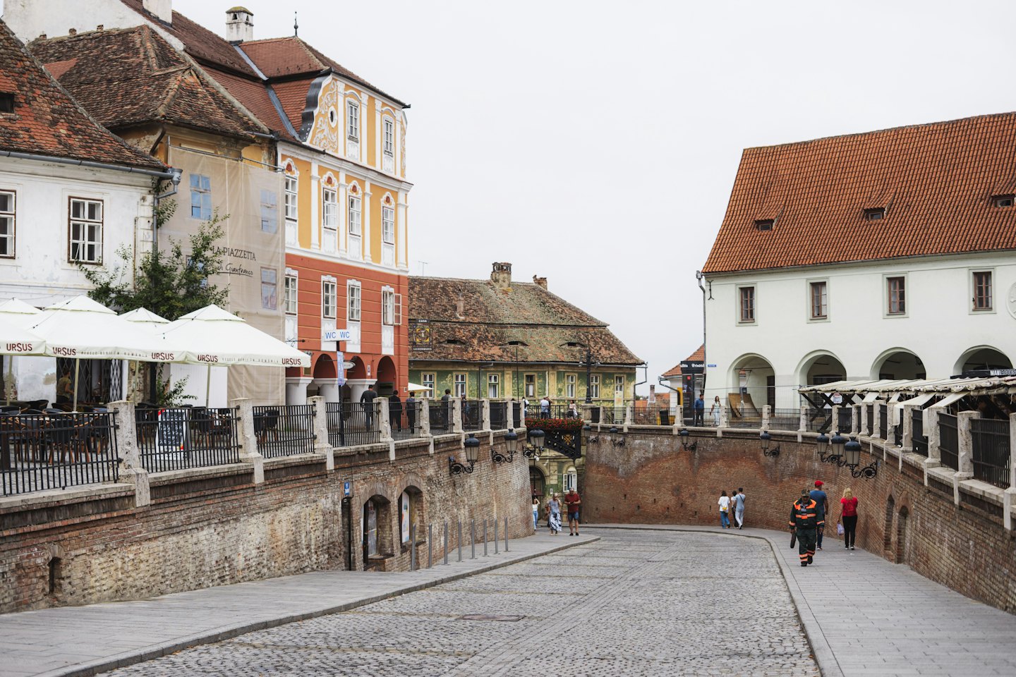 People walk along a cobblestone street with historic buildings.