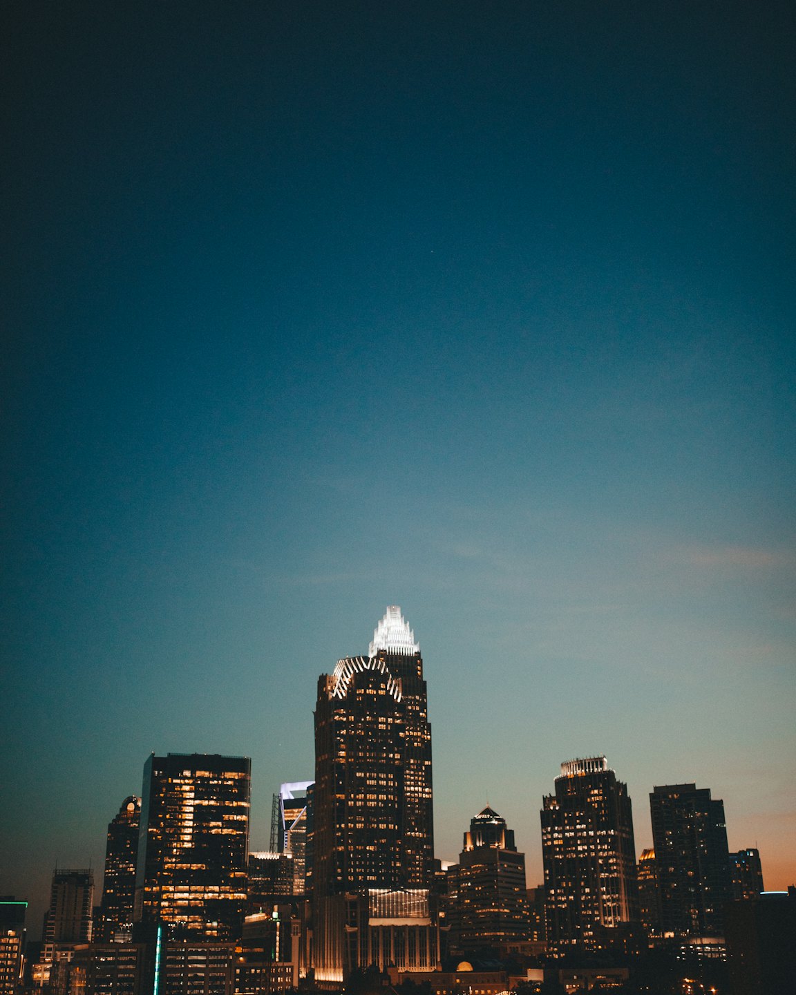 Modern city skyscrapers lit up at twilight.