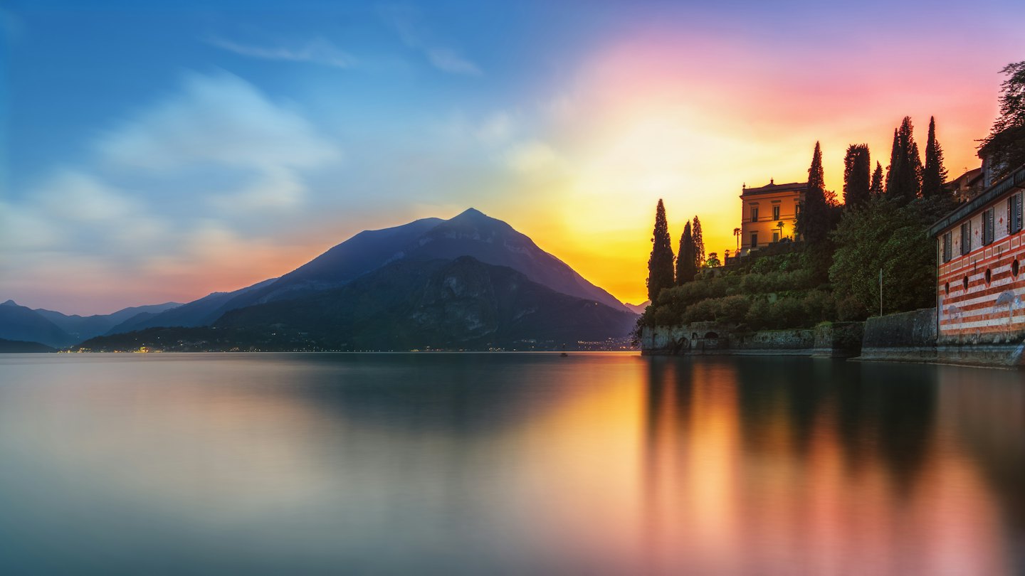 A villa and mountain landscape reflected in a calm lake.