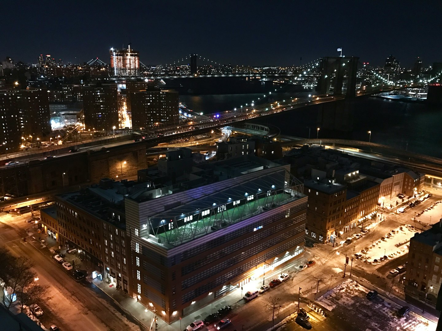 City buildings and a bridge glowing above a dark river.