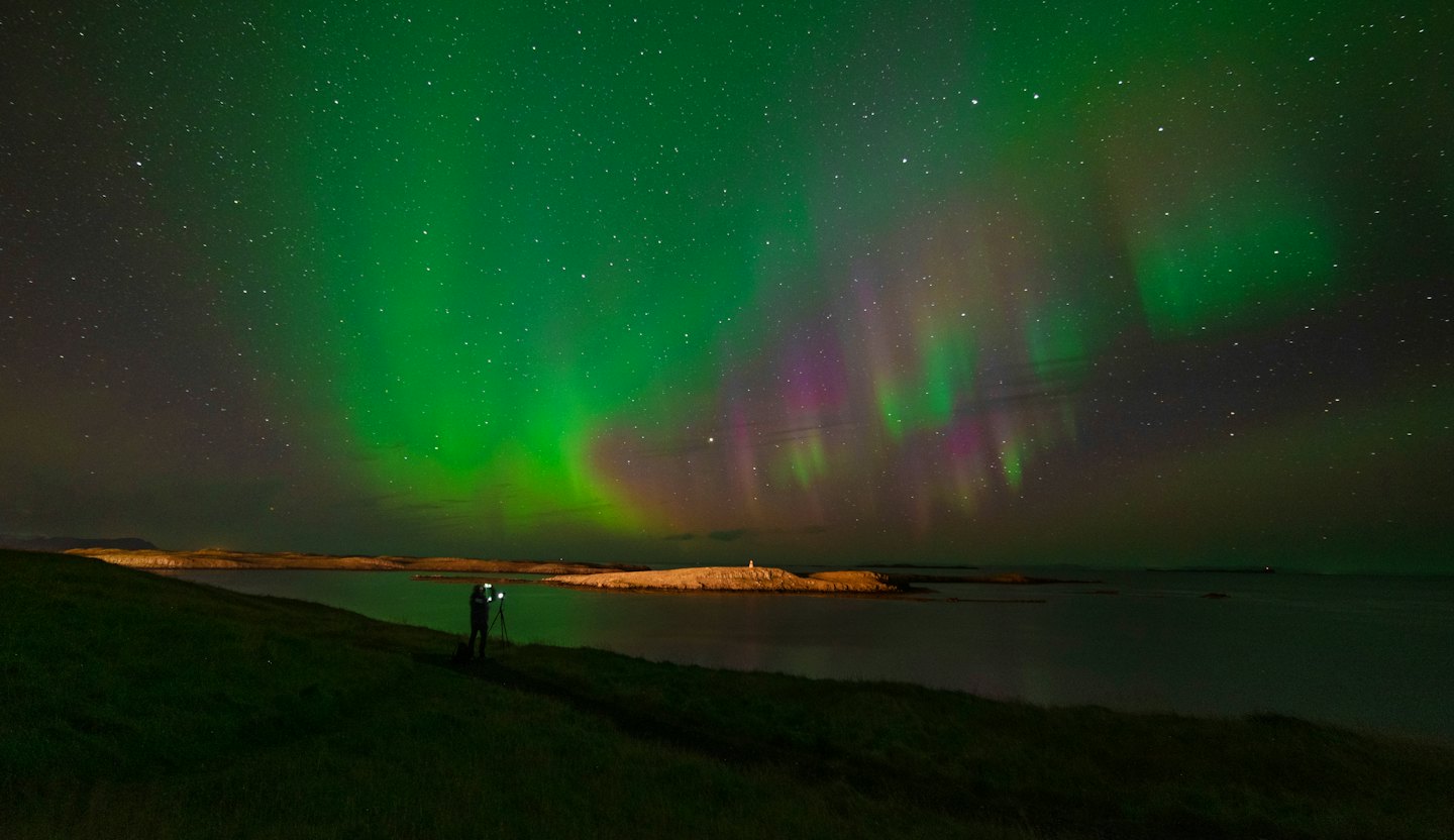 Photographer captures Aurora Borealis over starry night sky.