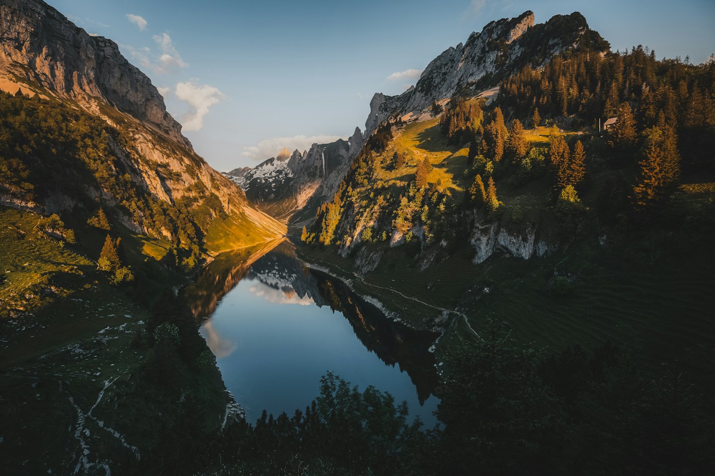 Mountain lake reflecting snow-capped peaks at sunset.